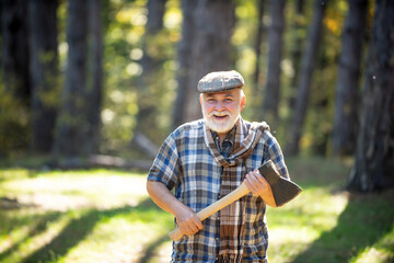 Naklejka na ściany i meble Hiking in deep wood. Sunny weather. Portrait of smiling man. Fashion portrait man. Natural background. Old bearded man with axe. Human and nature. Funny bearded forester.