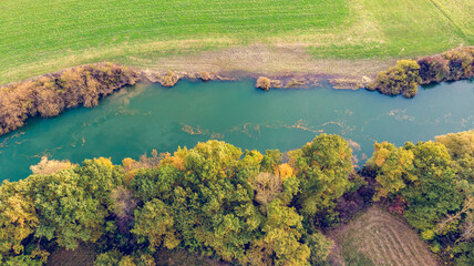 Drop down view of river flowing through fields after harvest.