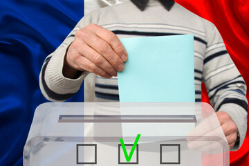 male voter drops a ballot in a transparent ballot box against the background of the national flag of France, concept of state elections, referendum