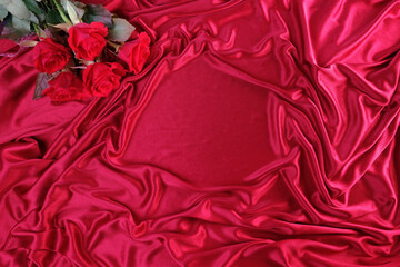 texture of luxury red silk fabric, background with waves and drapery for fashion design, copy space. bouquet of roses, concept of congratulations on wedding day, birthday, mother