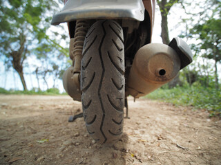 Fototapeta na wymiar Close-up view. Rear tire of scooter moped on a dirt road.