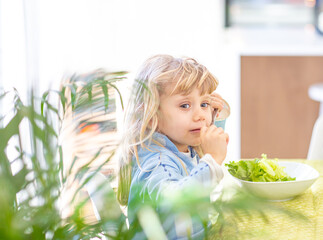 Small blonde girl refusing to eat vegetable salad. Lifestyle Concept
