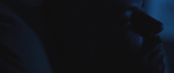 Close up of a soldier sitting alone in a dark room, staring to nowhere, dealing with PTSD.