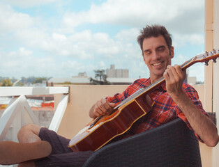 young man playing guitar on the balcony
