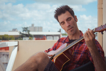 young man playing guitar on the balcony
