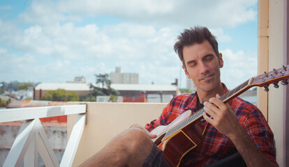 young man playing guitar on the balcony
