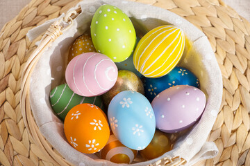 Easter colorful eggs in busket on white wooden table. Happy Easter background.