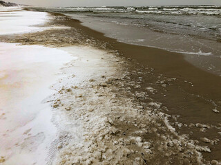 Snow-Dusted Sand Dunes in Winter Landscape. A serene winter landscape featuring sand dunes partially covered in snow, under a soft overcast sky. 