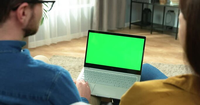 Close up of laptop with green screen. Caucasian family couple speaking on online video call on computer with chroma key sitting in apartment in good mood showing thumb up. Webcam conference