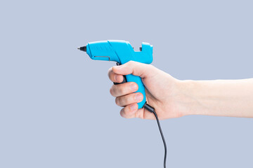 handyman holding glue gun isolated over gray background