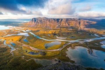 Beautiful, wild arctic valley viewed from mountain top in epic early morning light. Remote Rapa river valley from the top of Skierfe in Sarek national park in Swedish Lapland. Autumn colors.