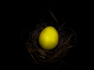 Closeup of Colourful  Easter egg in a nest isolated on Black background with a selective focus on Egg on the occasion of Easter . Copy space . Golden Egg .