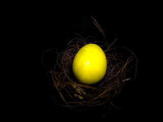 Closeup of Colourful  Easter egg in a nest isolated on Black background with a selective focus on Egg on the occasion of Easter . Copy space . Golden Egg .