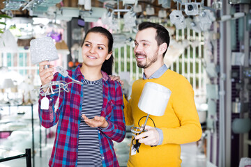 Young couple is considering buying a bedside lamp in a home-made goods store