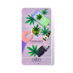 human hand holding cup of tea with medical cannabis leaves drugs consumption marijuana products at wooden background smartphone screen mobile app top angle view copy space