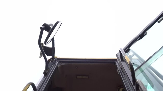 worker wearing a safety equipment climbing into yellow construction vehicle equipped with warning signs