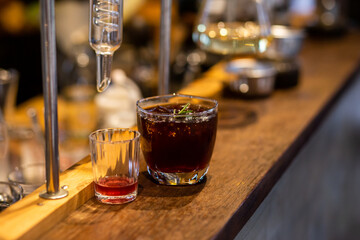 Close-up Americano is put ice in a clear glass in the distillation lab, placed on a table with a glass tube.