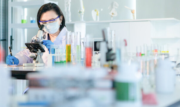 Scientis using microscope to work in lab.
