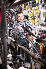 Smiling man inspects the handlebar of bike in a sporting goods store