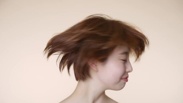 髪を振るショートヘアの女性　ヘアケアイメージ 