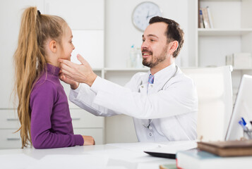 Obraz premium Little smiling girl visiting consultation with man doctor in hospital