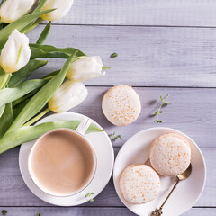 Obraz na płótnie Canvas Morning cup of coffee, cake macaron and spring tulip whate flowers on white wooden background. Flat lay.Beautiful breakfast for Women