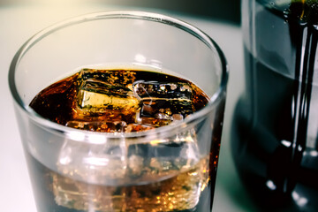 A glass of soda with ice cubes.