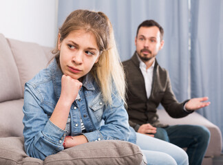 Young father having disagreement with daughter teenager at home
