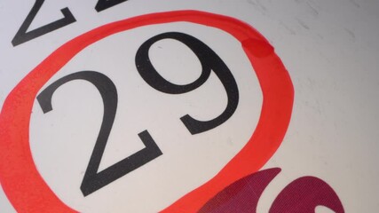 29 - Marking the date in the calendar with a red marker. The twenty-ninth day of the month. Deadline. The hand circles the date in the calendar with a pen. Number in the red circle close up