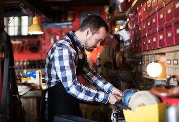 Fototapeta premium Positive male worker preparing buckle for belt in leather workshop