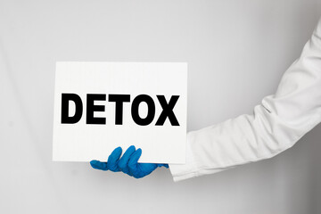 The doctor's blue - gloved hands show the word DETOX - . a gloved hand on a white background. Medical concept. the medicine