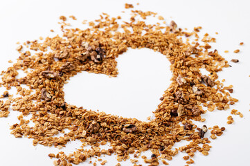 homemade granola with nuts in the form of a love heart symbol on a white table, top view