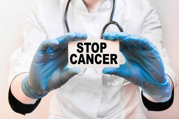The doctor's blue - gloved hands show the word STOP CANCER - . a gloved hand on a white background. Medical concept. the medicine