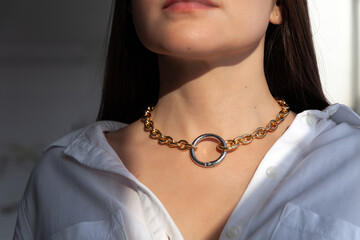 Beautiful model brunette in modern gold metal necklace chain