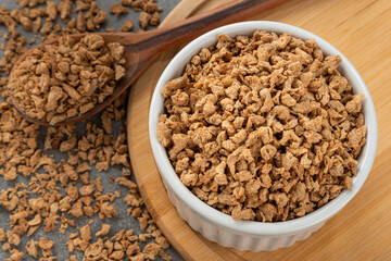 Bowl with soy protein grains. Detail of wooden spoon and bamboo holder.