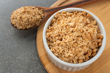 Bowl with Brazilian farofa with soy protein. Detail of wooden spoon and bamboo holder.