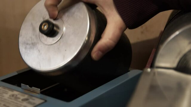Person picking up rock tumbling barrel after is has spun for a week with rocks and grit as part of the polishing process.