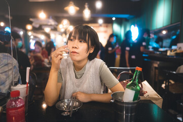 Portrait happy smile young adult asian woman cheer with soju at Korean restaurant.