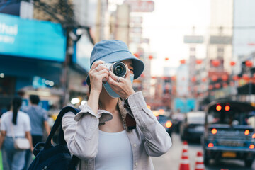 Young adult asian woman backpack traveller wear face mask take a photo by camera.