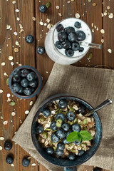 Oatmeal porridge with blueberries in a ceramic bowl and glass of chia pudding on a wooden background. Top view.