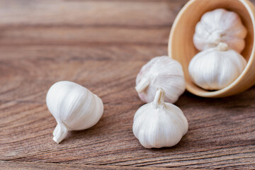 Garlic bulb in wooden bowl isolated on old rustic wood table background .