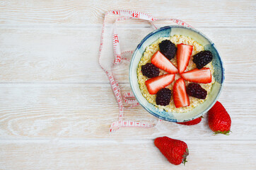 healthy breakfast oatmeal porridge with fresh fruit blackberries and strawberry on a wooden background, copy space text