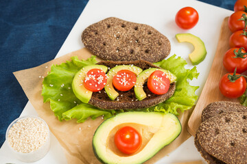 Healthy food. Avocado Sandwich. Rye bread with bran, Cherry Tomatoes, Avocado,Lettuce and Sesame Seed
