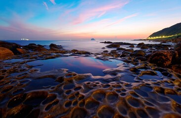 Naklejka premium Beautiful scenery of sunrise by rocky coast in northern Taiwan with reflection of golden sunlight on smooth sea water (long exposure effect) The famous attraction 