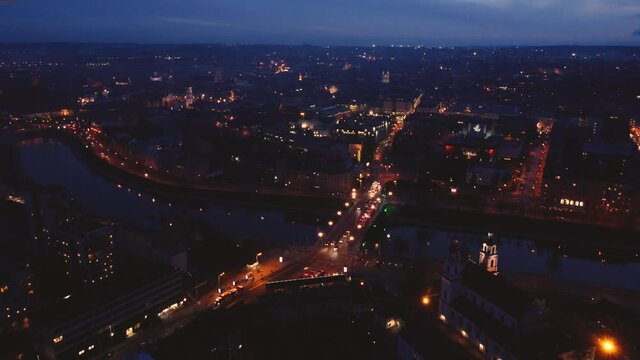 Aerial footage of traffic crossing bridge over Neris river, Vilnius, Lithuania at night. Drone high angle.