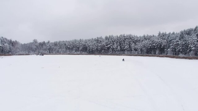 Dare devils racing motorcycles on snowy field. Aerial wide shot.