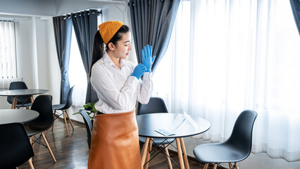 Asian woman waitress wearing glove and face shield to prevent and stop coronavirus before working