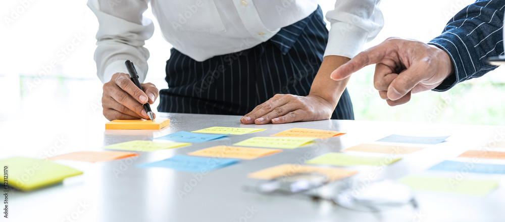Poster Two creative business people meeting and planning use post it notes sticky note on desk to share idea, Analysis data chart and graph with teamwork strategy brainstorming in office