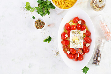 Preparation of ingredients for fetapasta. Trending Feta bake pasta recipe made of cherry tomatoes, feta cheese, garlic and herbs.  Top view, above, copy space.
