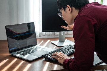 Asian man programmer looking and touching on screen laptop to typing code data with keyboard about website